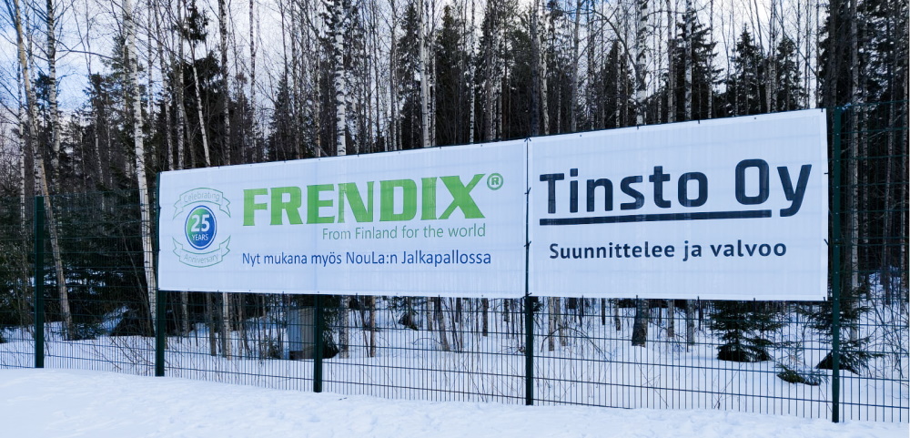 Valkoinen banneri kiinnitetty aitaan ja bannerissa lukee Frendix From Finland for the world, Frendix mukana myös NouLa:n jalkapallossa.